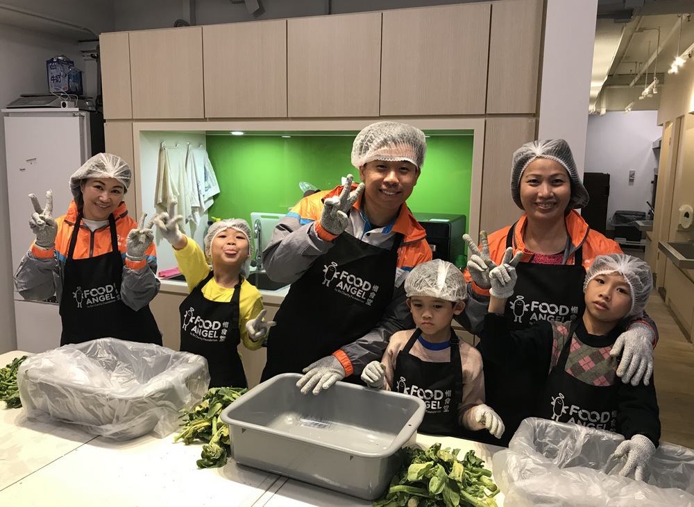 Volunteers and children help prepare meal boxes for the elderly